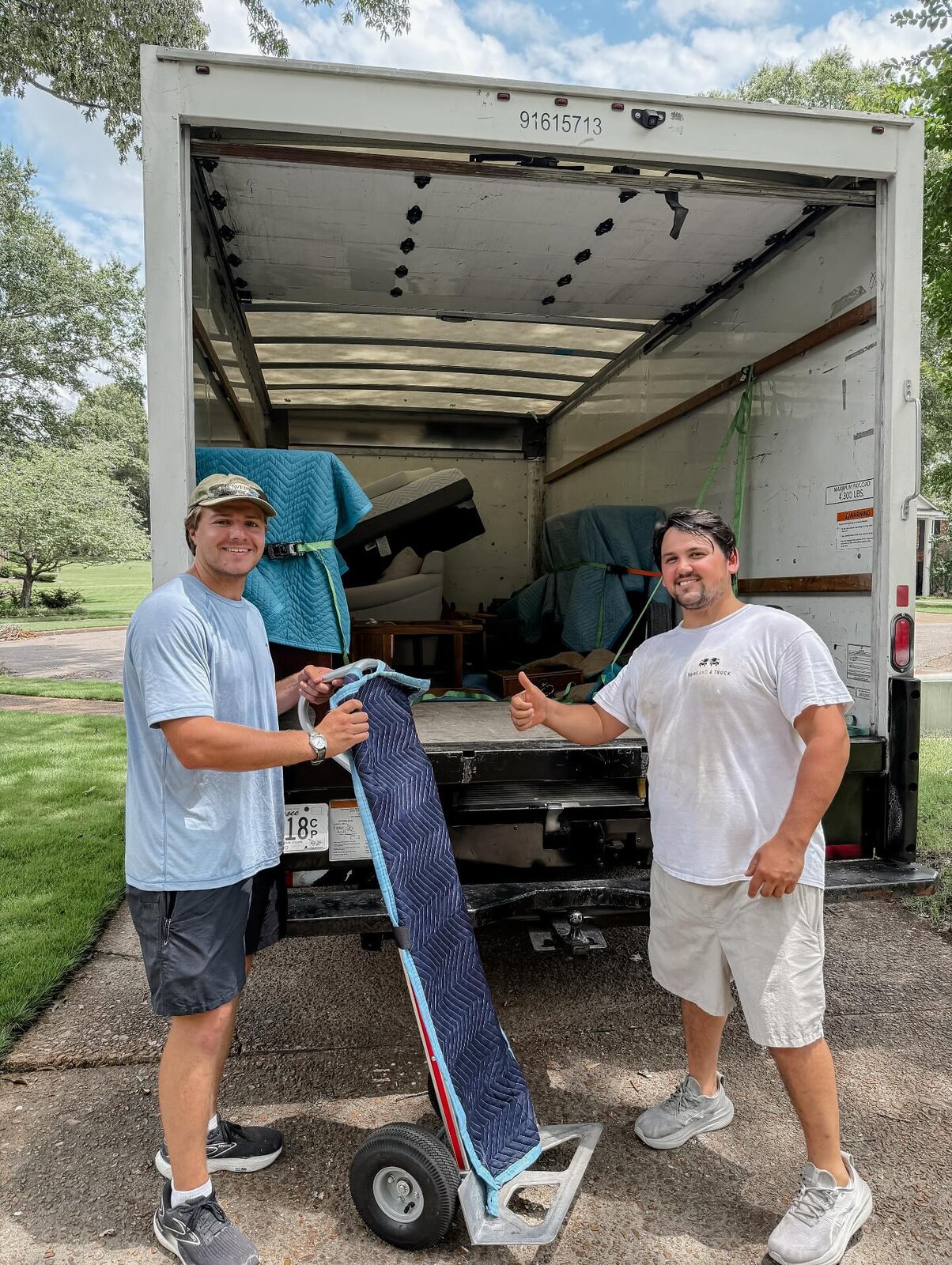 Two Twins and a Truck crew members giving a thumbs up at the back of a carefully loaded moving truck